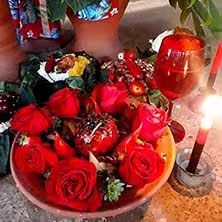 Oferenda com rosas vermelhas e velas acesas